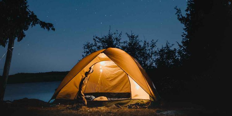 Glowing camping tent under starry night sky