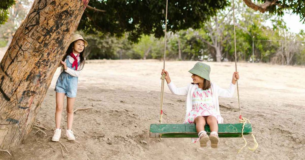 two girls playing on a swing