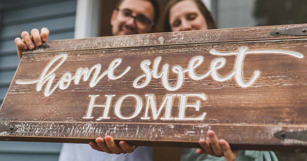 couple with wooden home sweet home sign