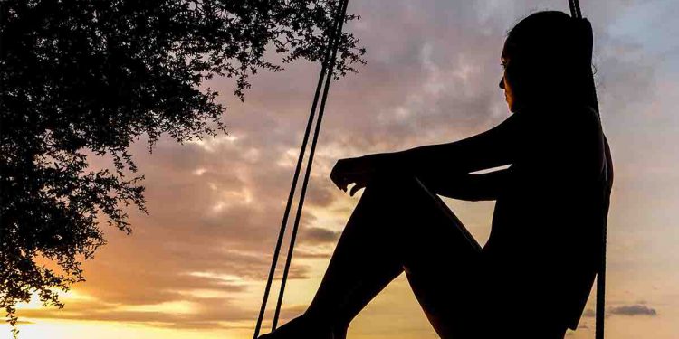 Silhouette of woman on swing during golden hour