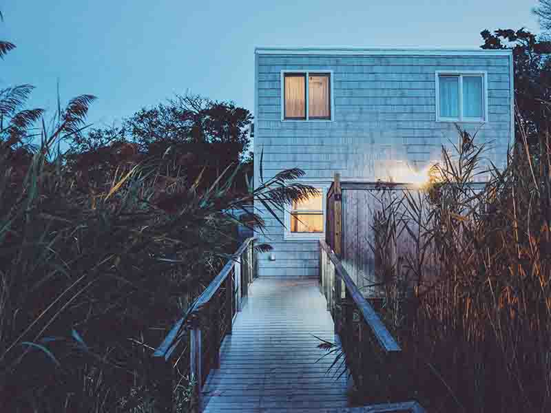 Small gray vacation home with wooden shingles at dusk