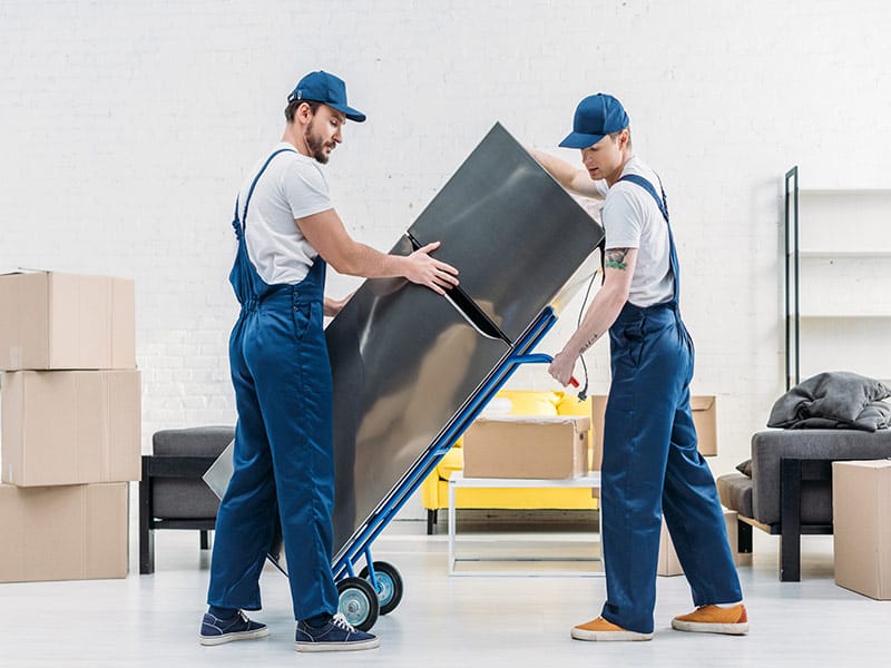 2 men loading a refrigerator on a dolly