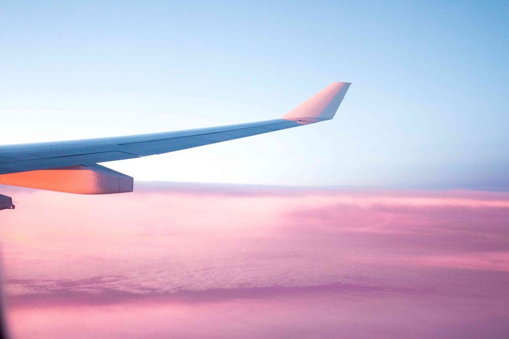 Gap year - airplane wing flying over pink clouds