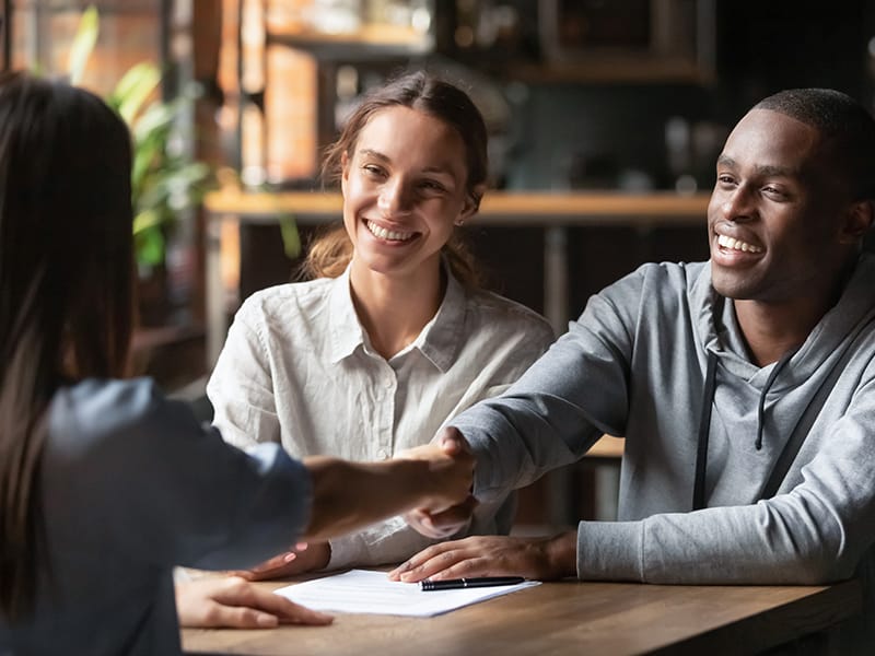 couple at table shaking hands with person
