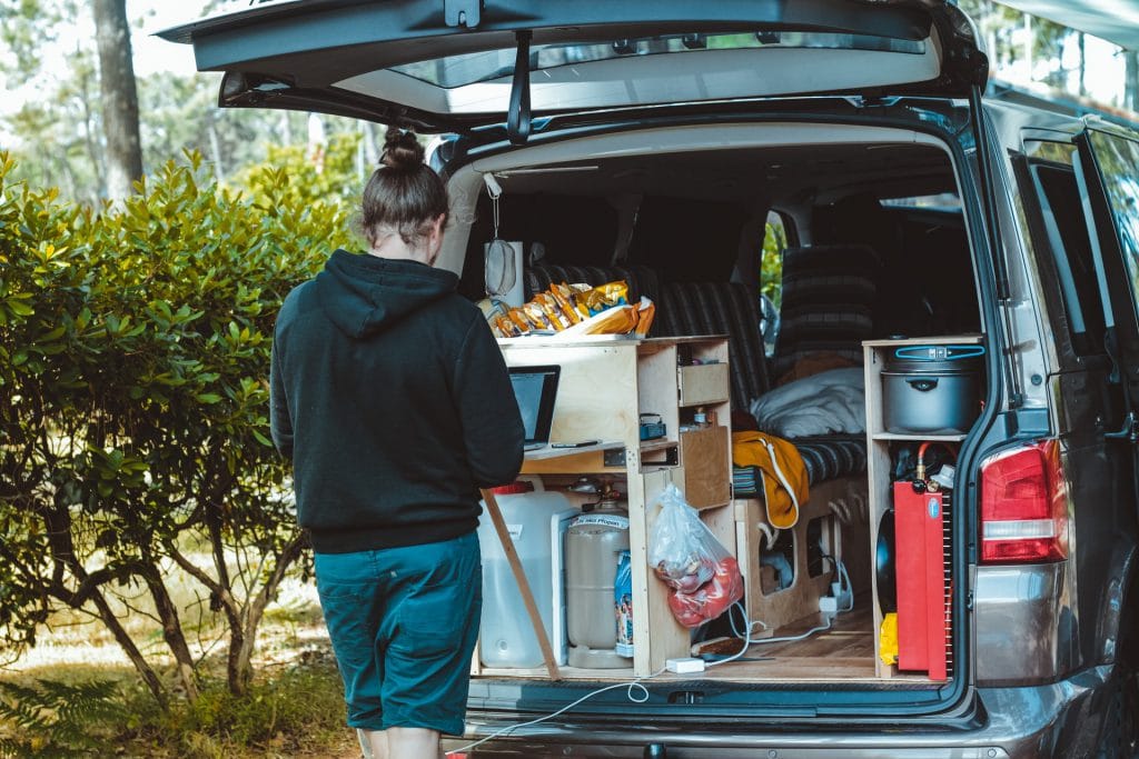 Man working on laptop behind his open camper van