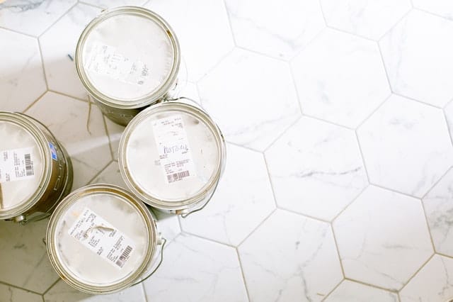 tops of four cans of paint on white hexagon tile floor